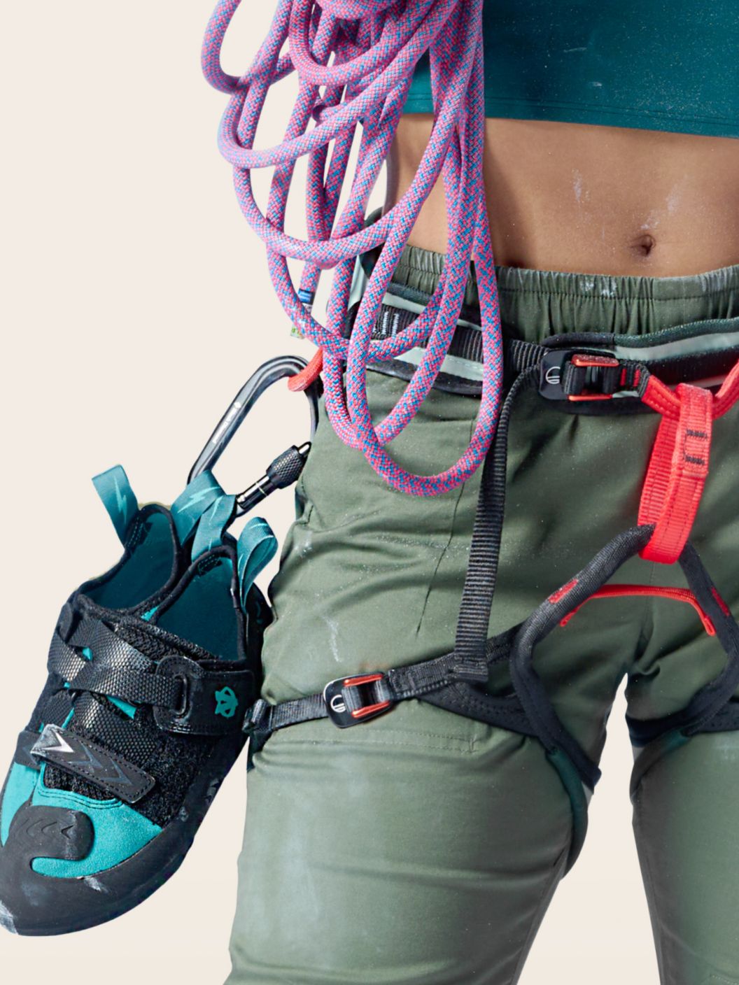 A person wearing a climbing harness with shoes and a rope attached.