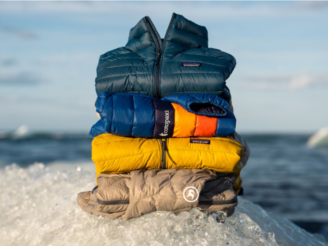 Four jackets folded and stacked on top of each other on ice.