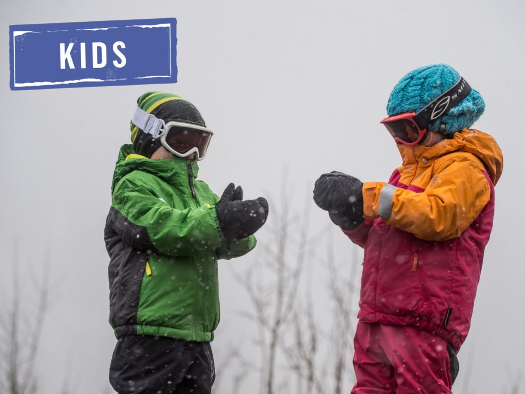 Two kiddos wearing snow kits, mittens, beanies, and goggles. 