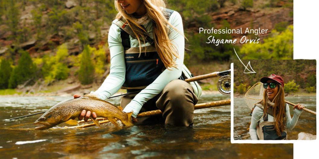 A woman kneels into a mountain river and holds a Brown Trout with its side facing outward.