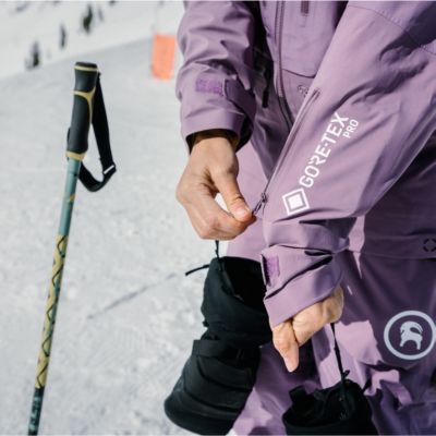Woman zipping up ski jacket sleeve pocket. 