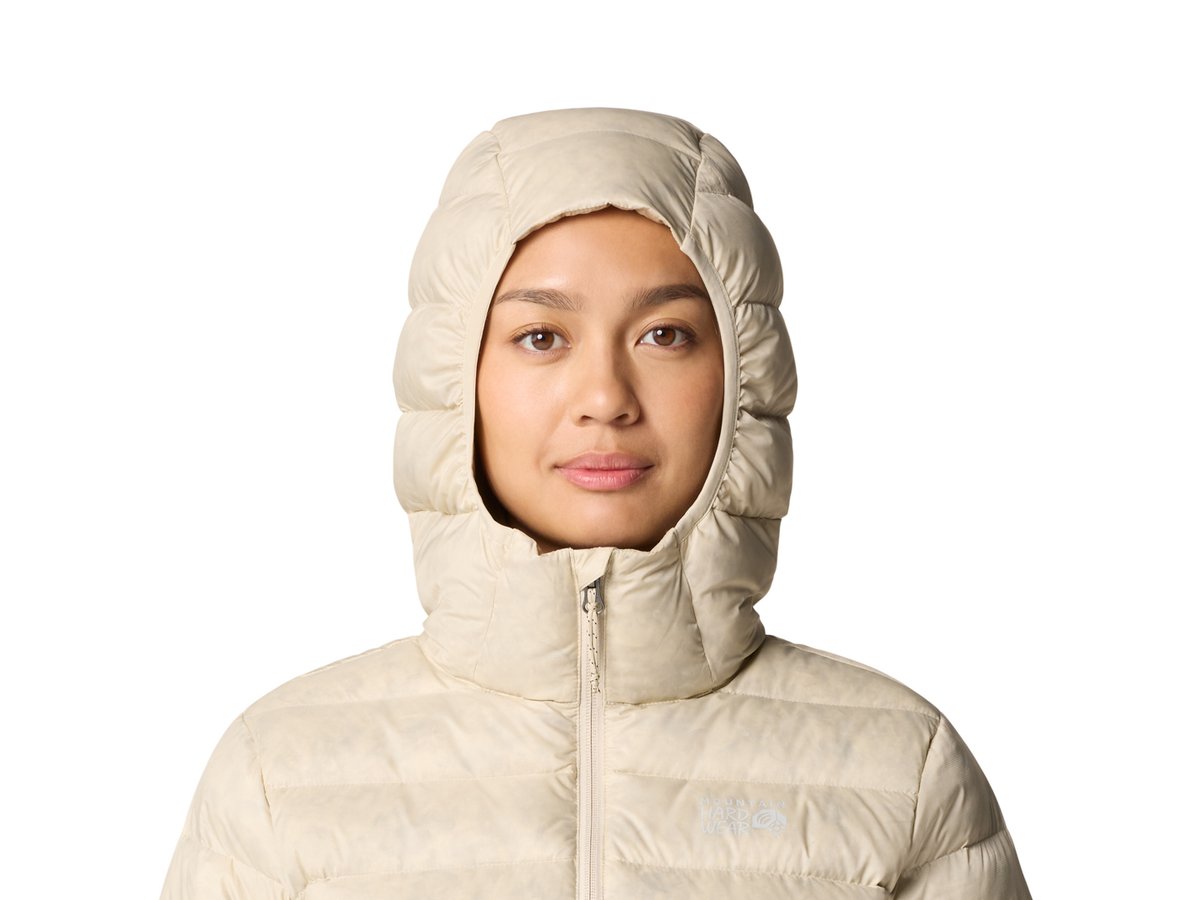 A woman wears a beanie, Mountain Hardwear Tiberondack Down Parka, and a bag slung over her shoulder.