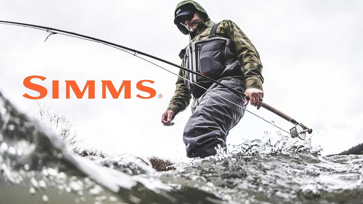 A fly fisherman in waders and tactical gear stands in a shallow stream while casting his fishing rod with water splashing around his feet.