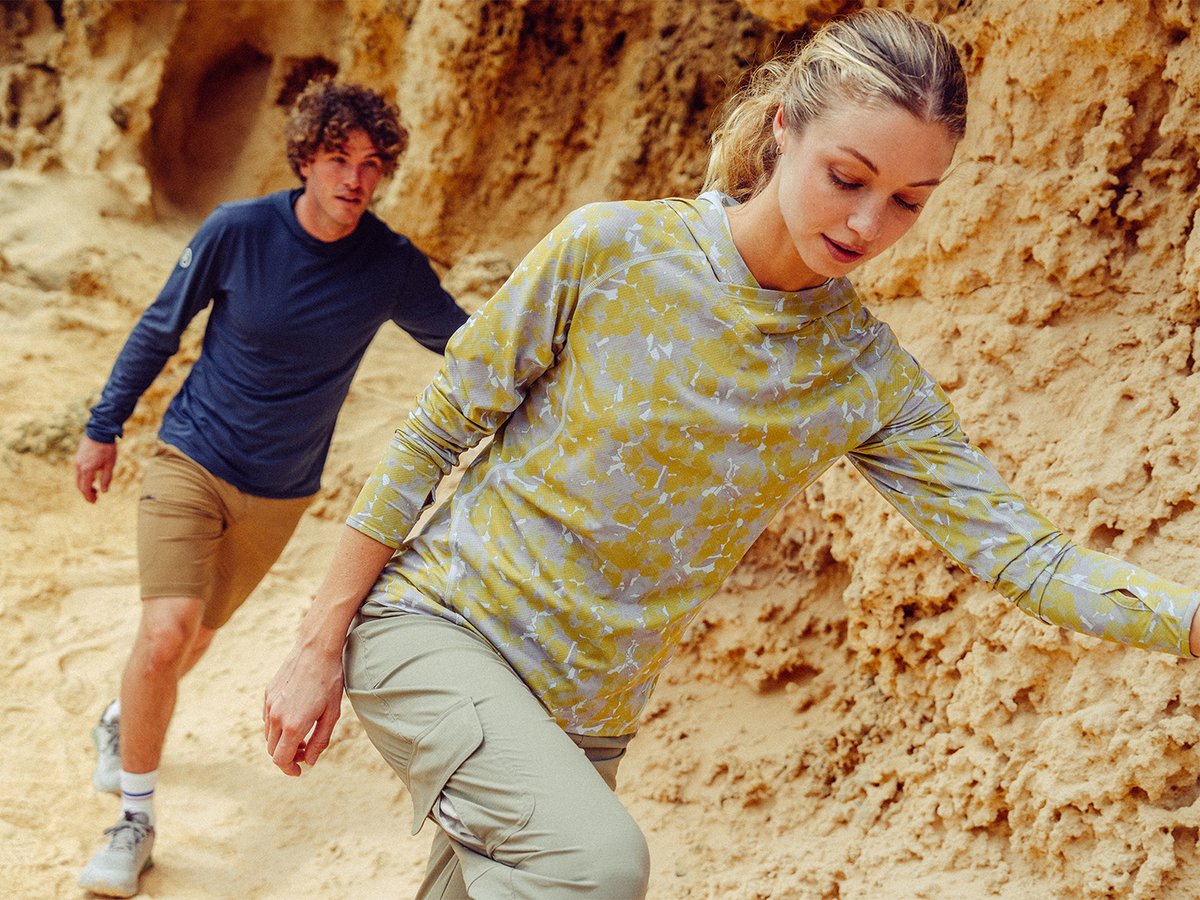 Two people hiking on sandy rocky path wearing ripstop bottoms and sun shirts.