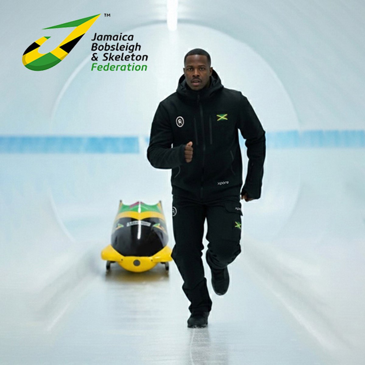 Jamaica bobsleigh team member on bobsleigh track with bobsled in the background.