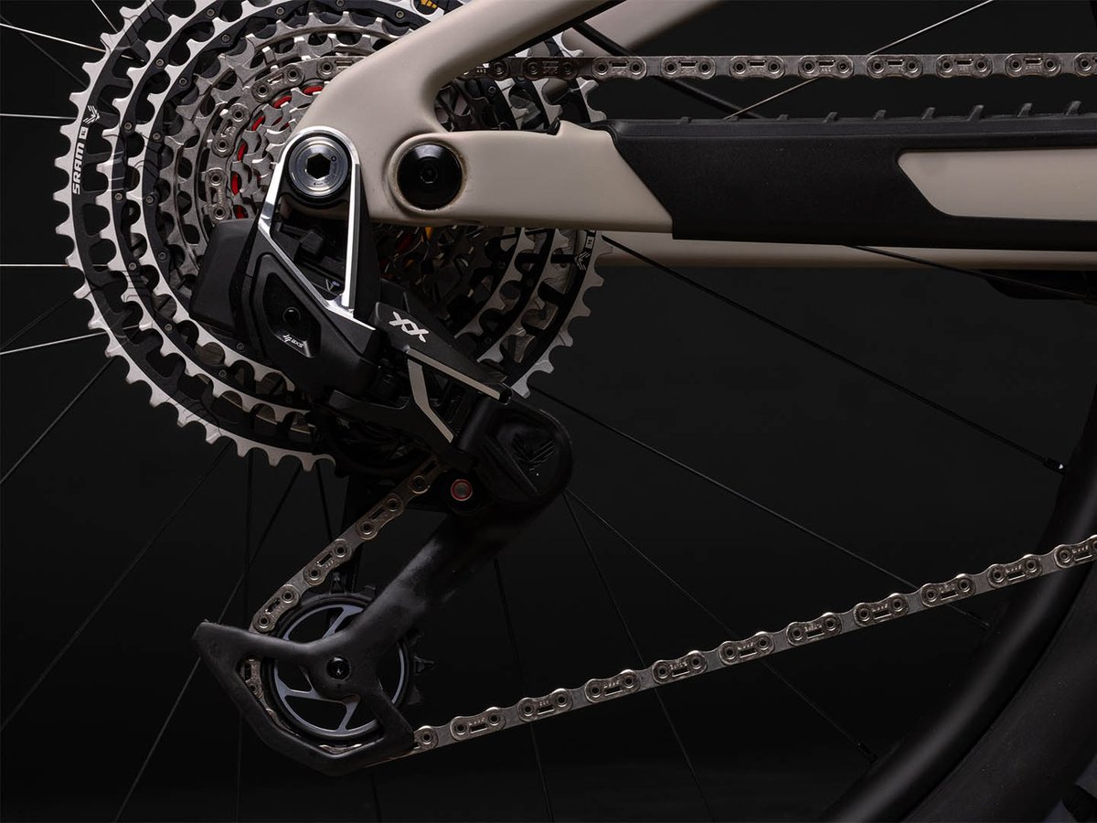 Rear derailleur detail showing SRAM XX cassette and chain on a tan frame, with derailleur cage and mount visible.