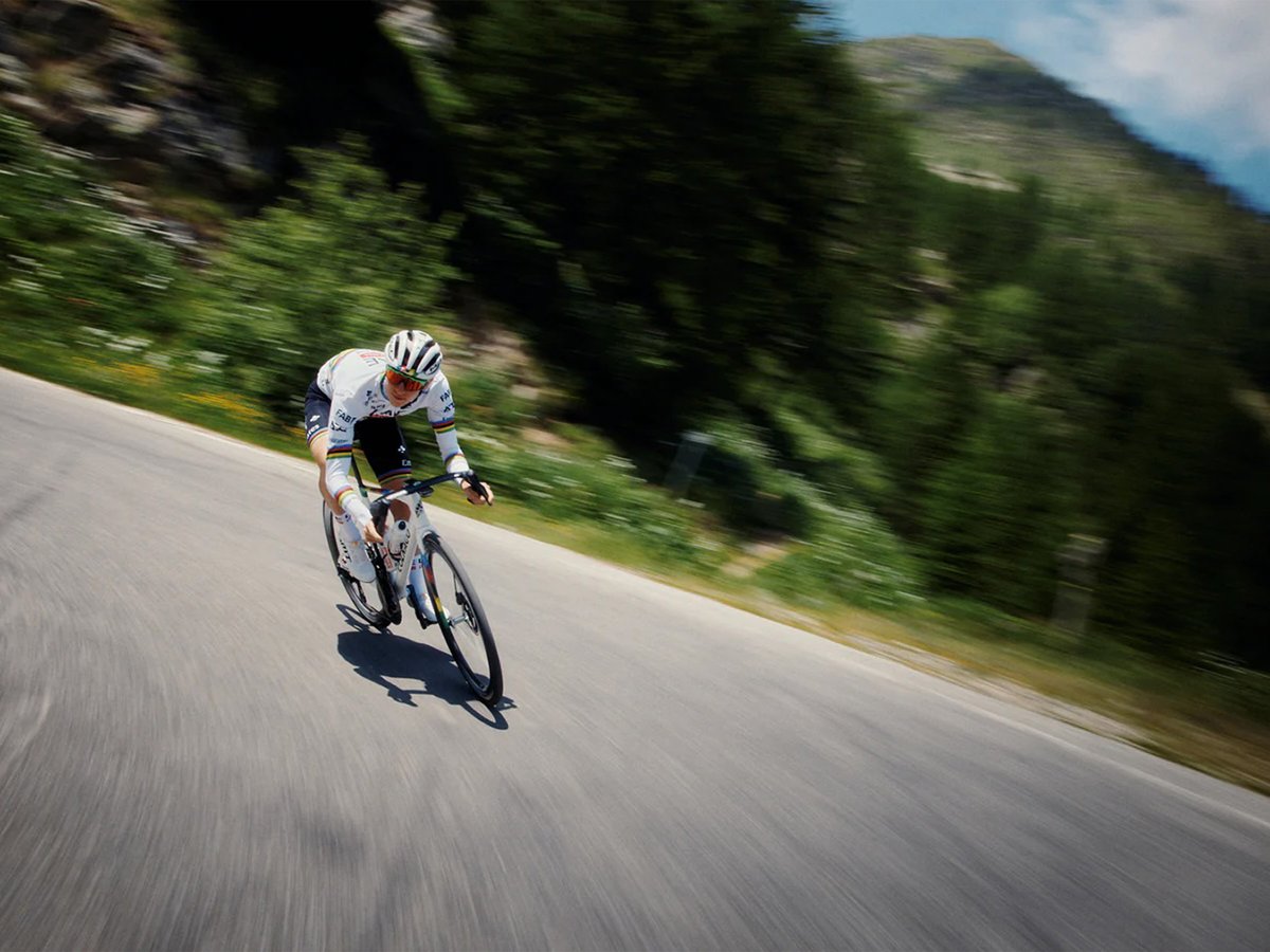 Lone cyclist riding around the bend of a paved road.