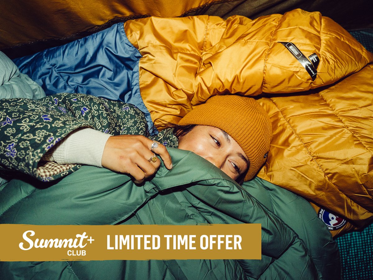Person bundled in sleeping bags at camp wearing a beanie. Summit+ Club limited time offer.