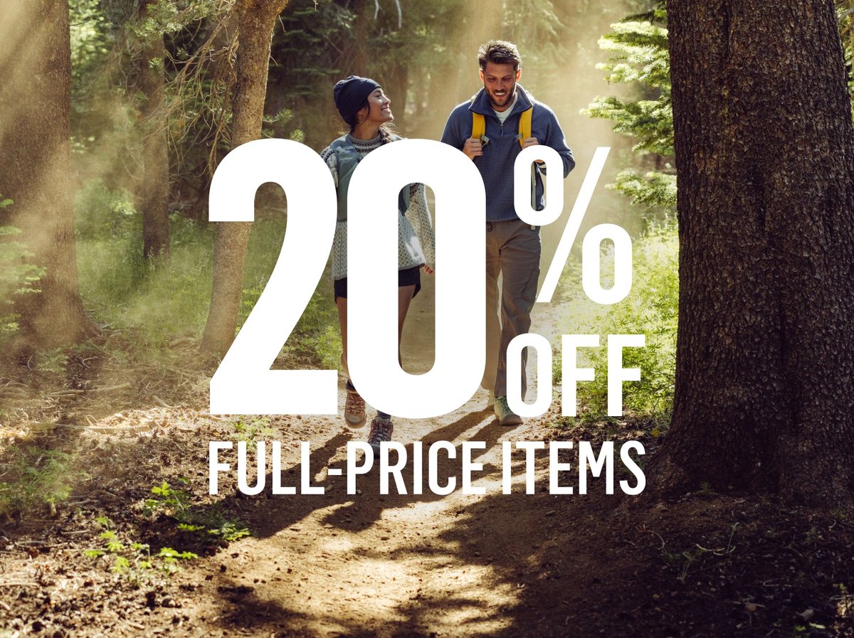 Two people hiking a sun-dappled forest trail in knitwear and hiking boots. Text reads: 20% off full-price items.