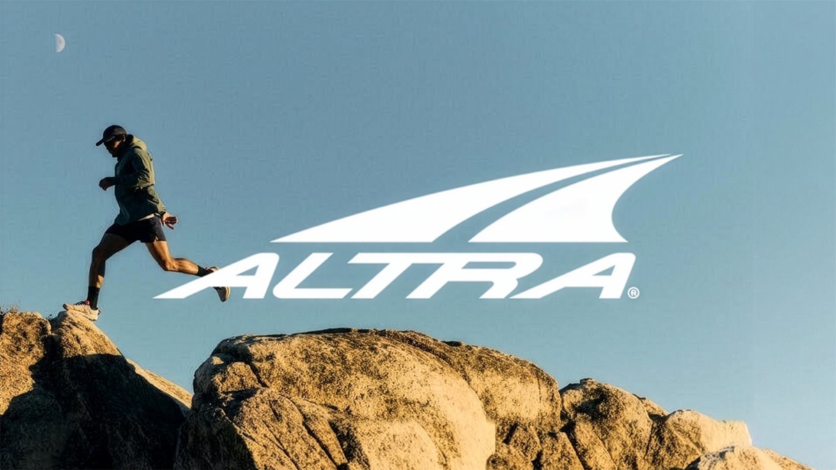A runner in motion jumping over gap across the top of boulders wearing Altra running shoes, with the brand's white logo in the center.