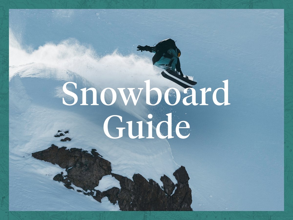 A splitboarder hucks off a cliff on a pow day. Overlaid text reads “Snowboard Guide.”