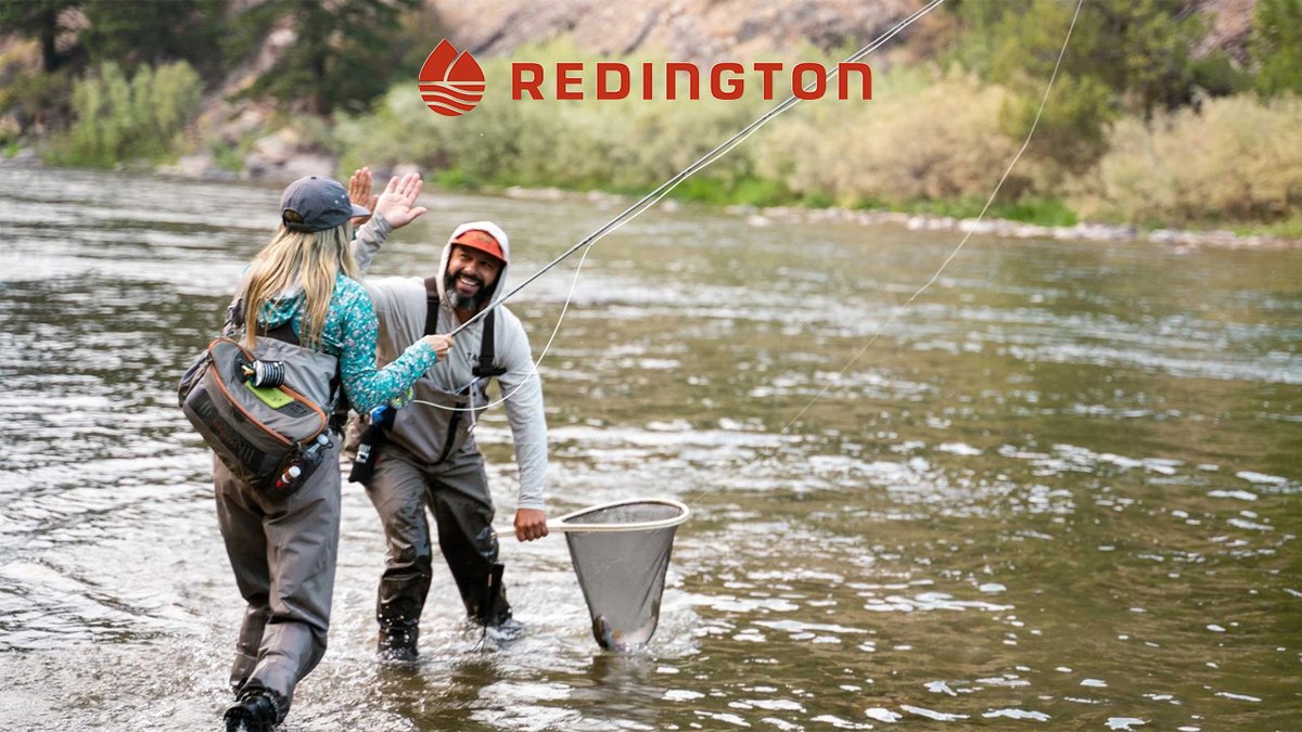 Two fly fishers high five in a river while wearing Redington waders and gear.