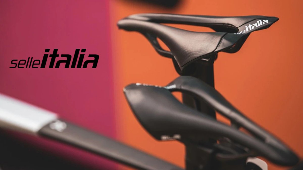 Selle Italia black bicycle saddle with branded text displayed against a vibrant pink and orange background showcasing premium cycling seat design.