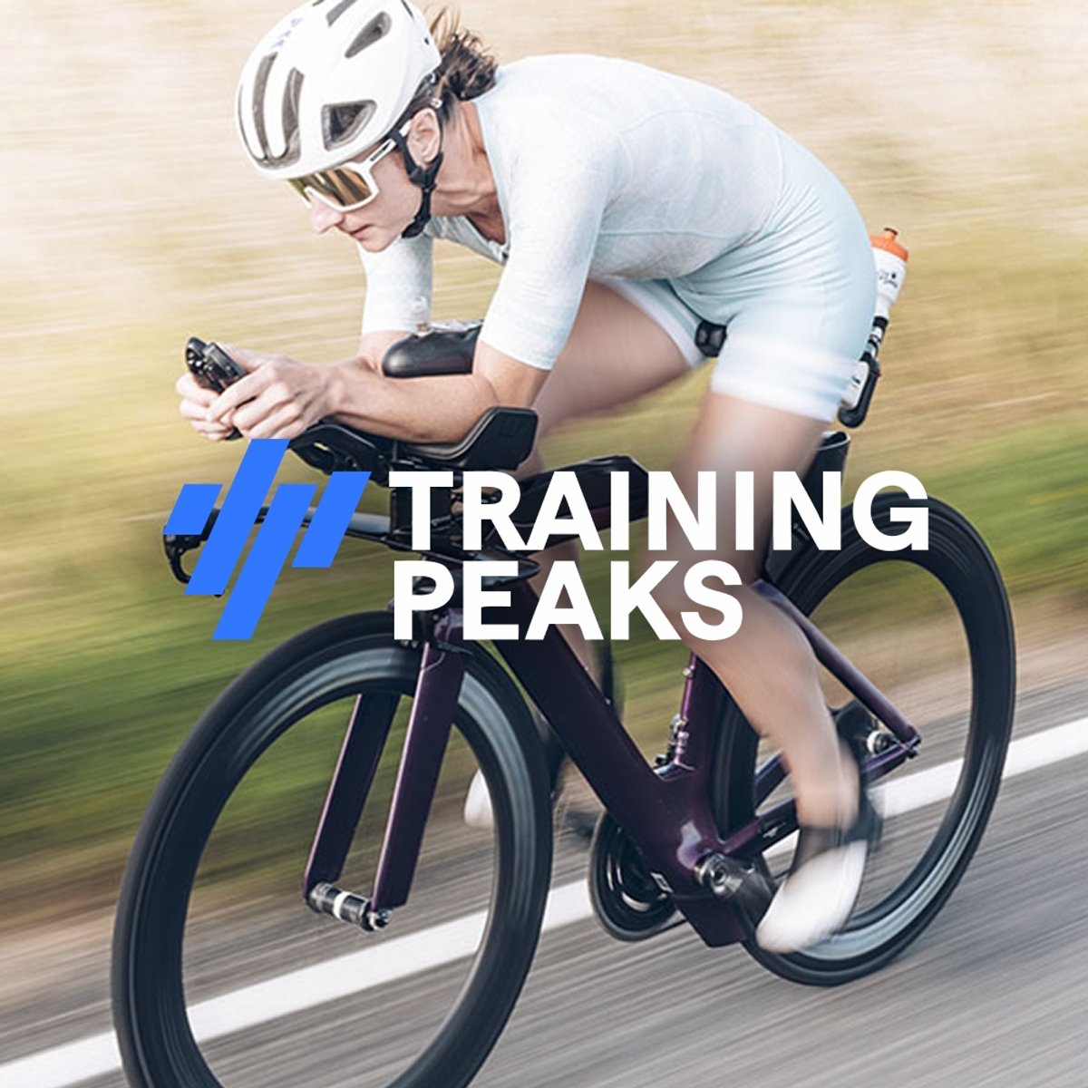 A cyclist in an aero position on a triathlon bike, wearing a white kit and helmet, riding fast on a road. Featuring the TrainingPeaks logo overlaid.