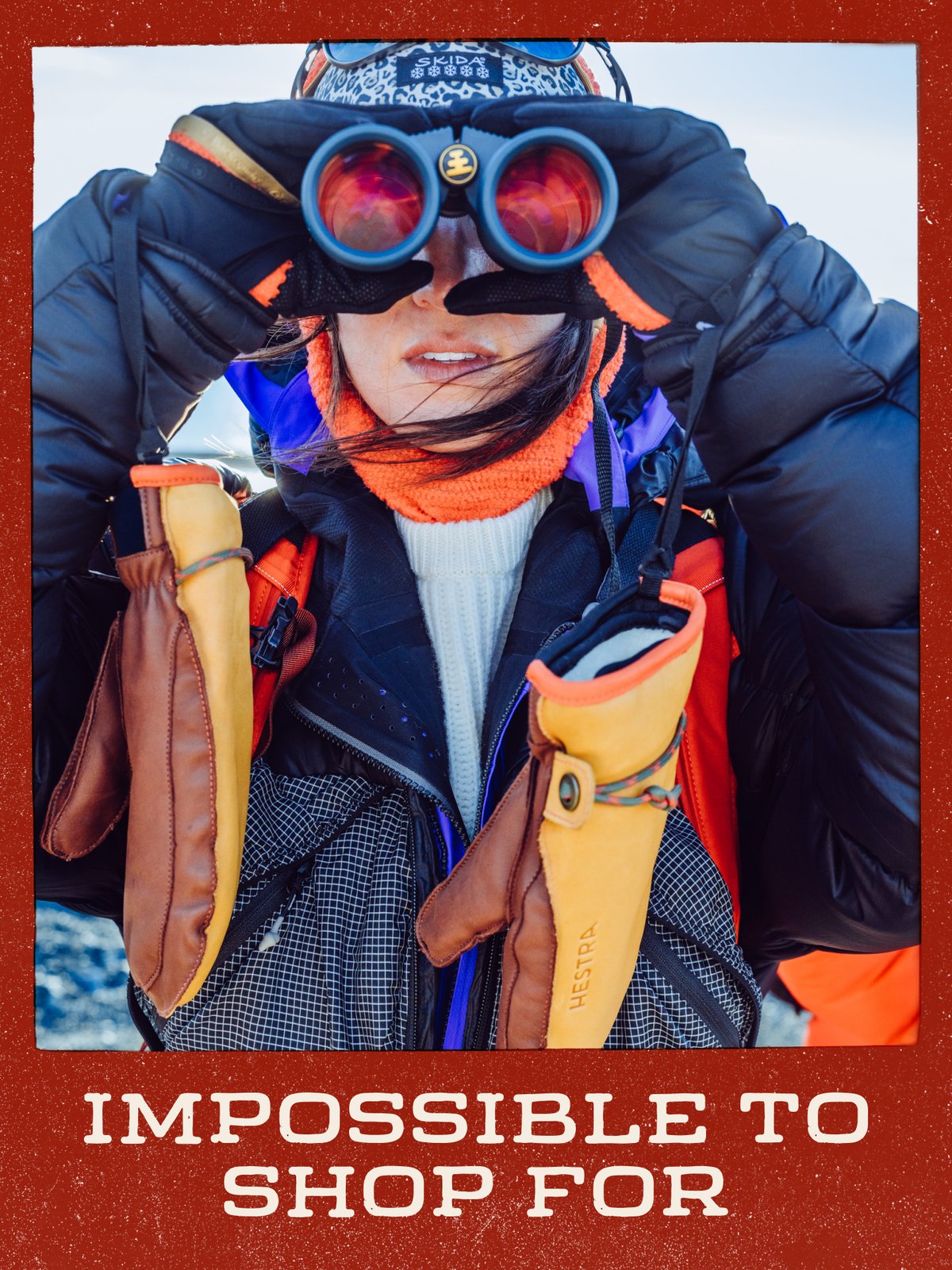 Person in a puffy jacket looking through binoculars, with leather mittens hanging at their chest: “Impossible to Shop For.”