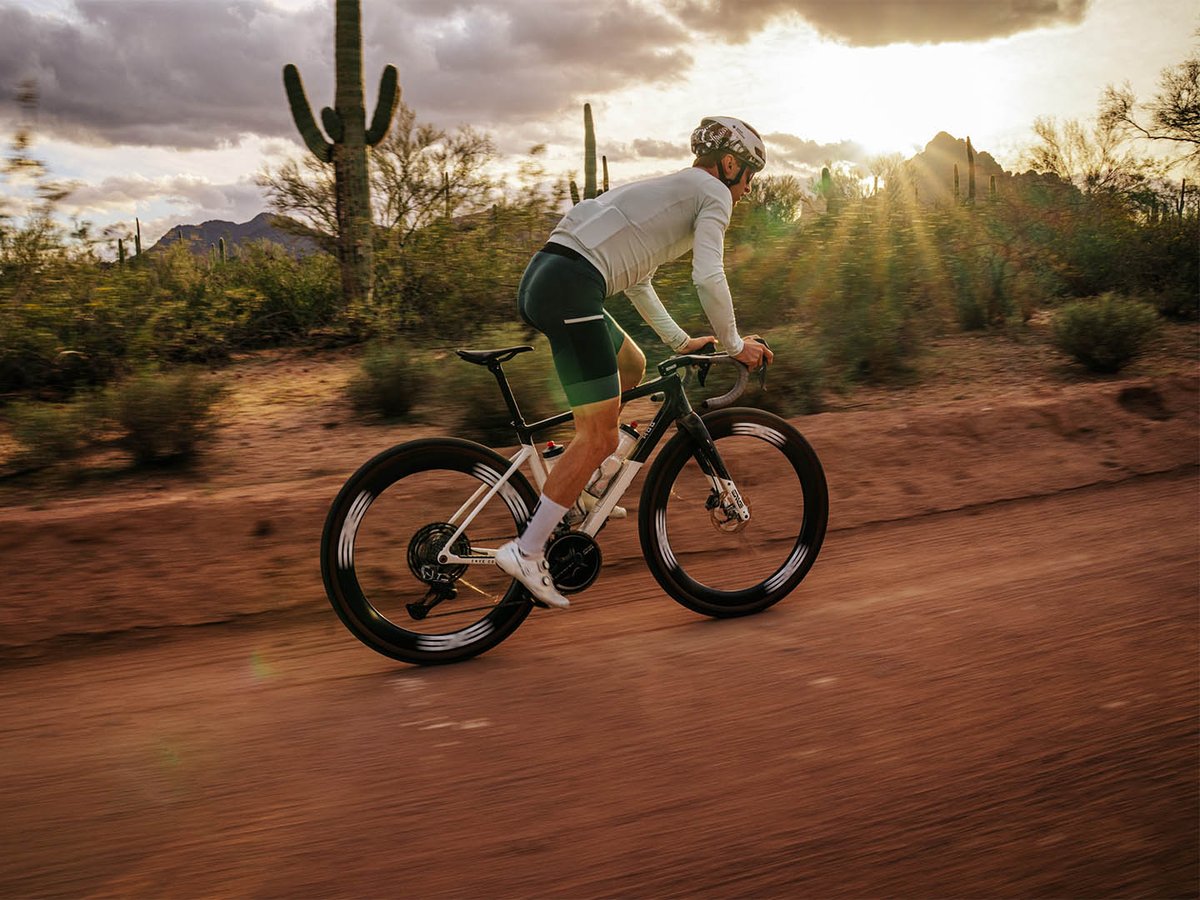 Gravel rider pedaling fast  on dirt road in the desert. 
