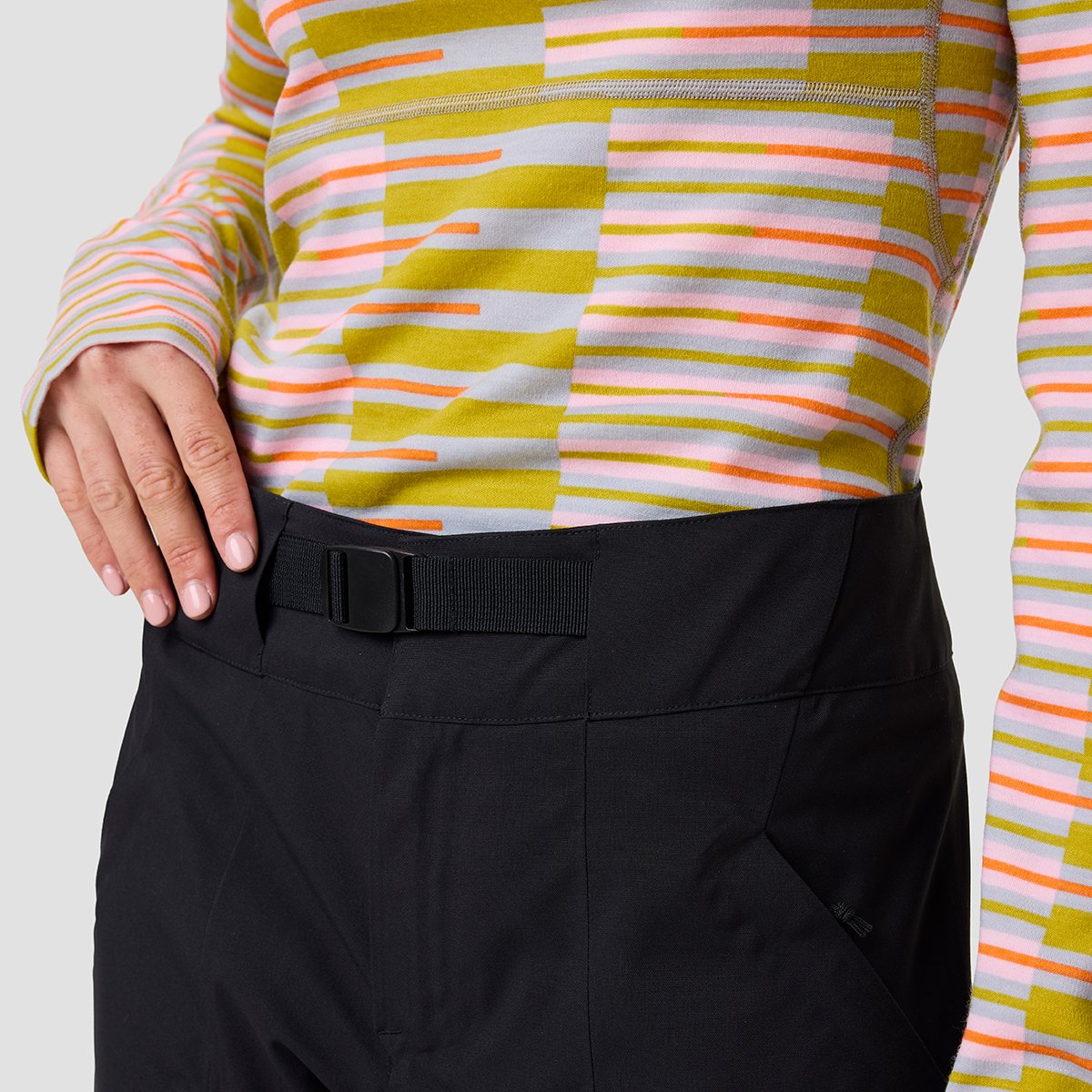 Person wearing ski pants with built in belt and thermal top holding their wasitband.