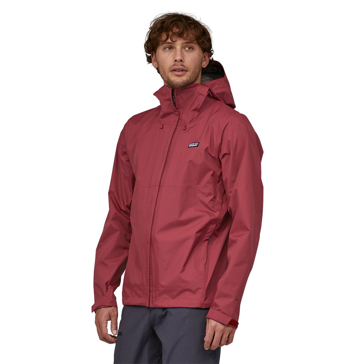 A side view of a man wearing a red Patagonia Torrentshell 3L. 