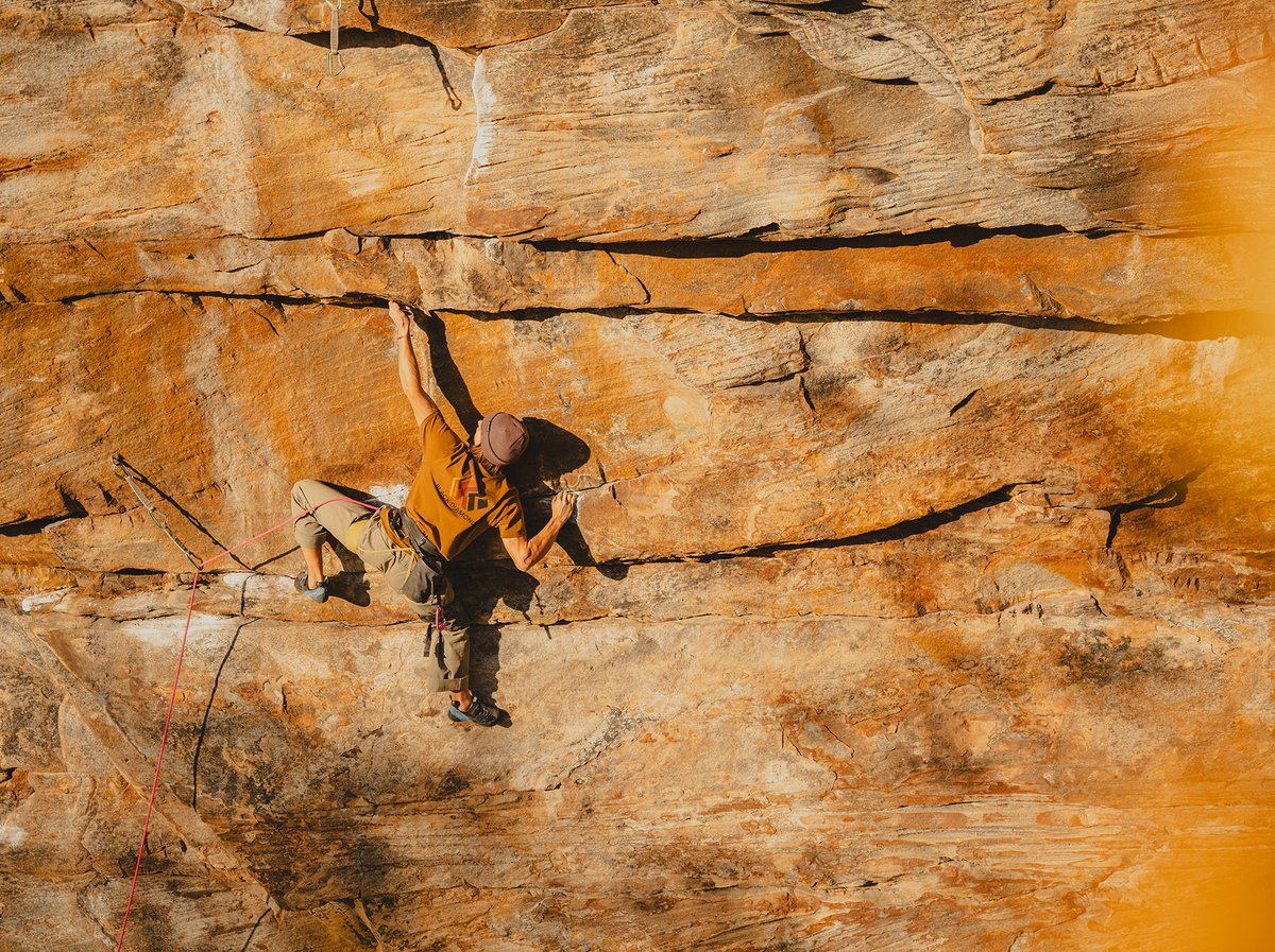 A man reaches for a hold on a big wall.