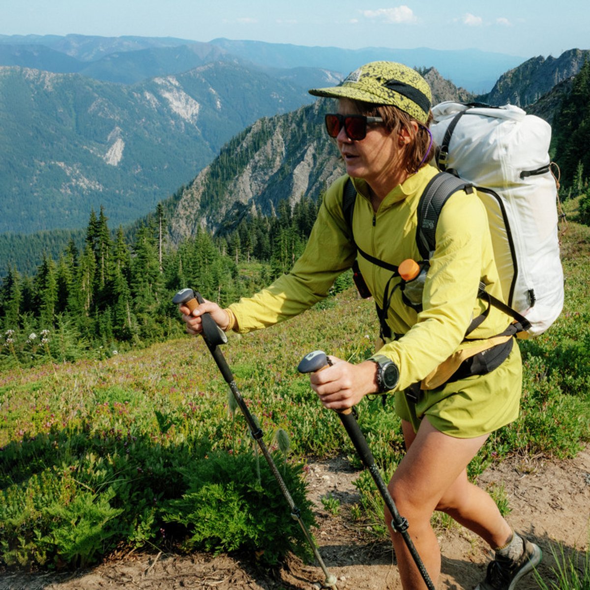 A woman hikes along a mountain ride, wearing a Sunshield top.