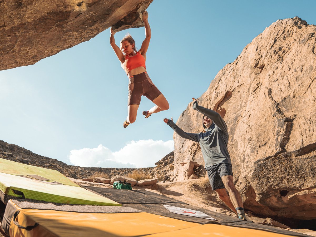 A man reaches for a hold on a big wall.