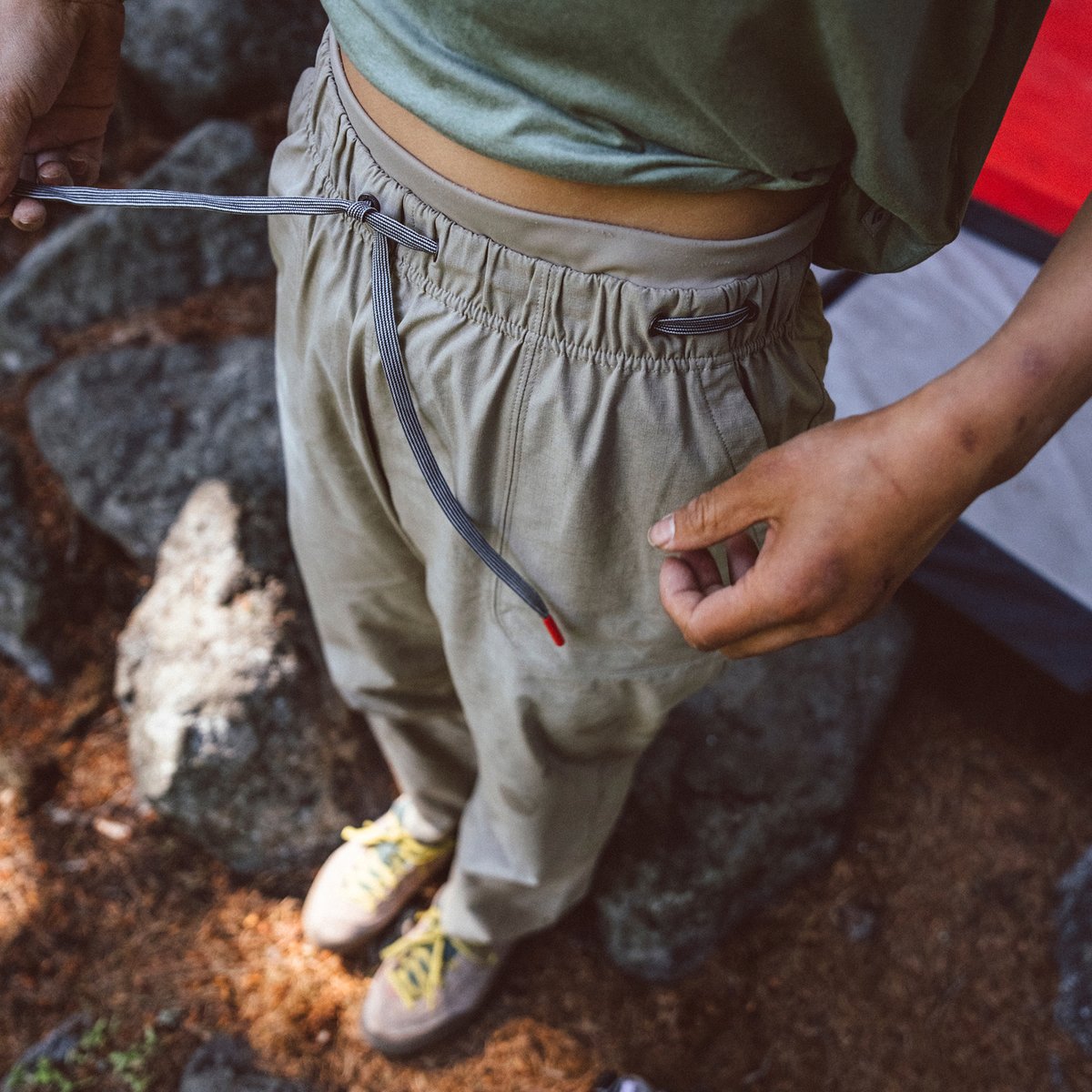 A woman ties the waistband string of her climbing pants.