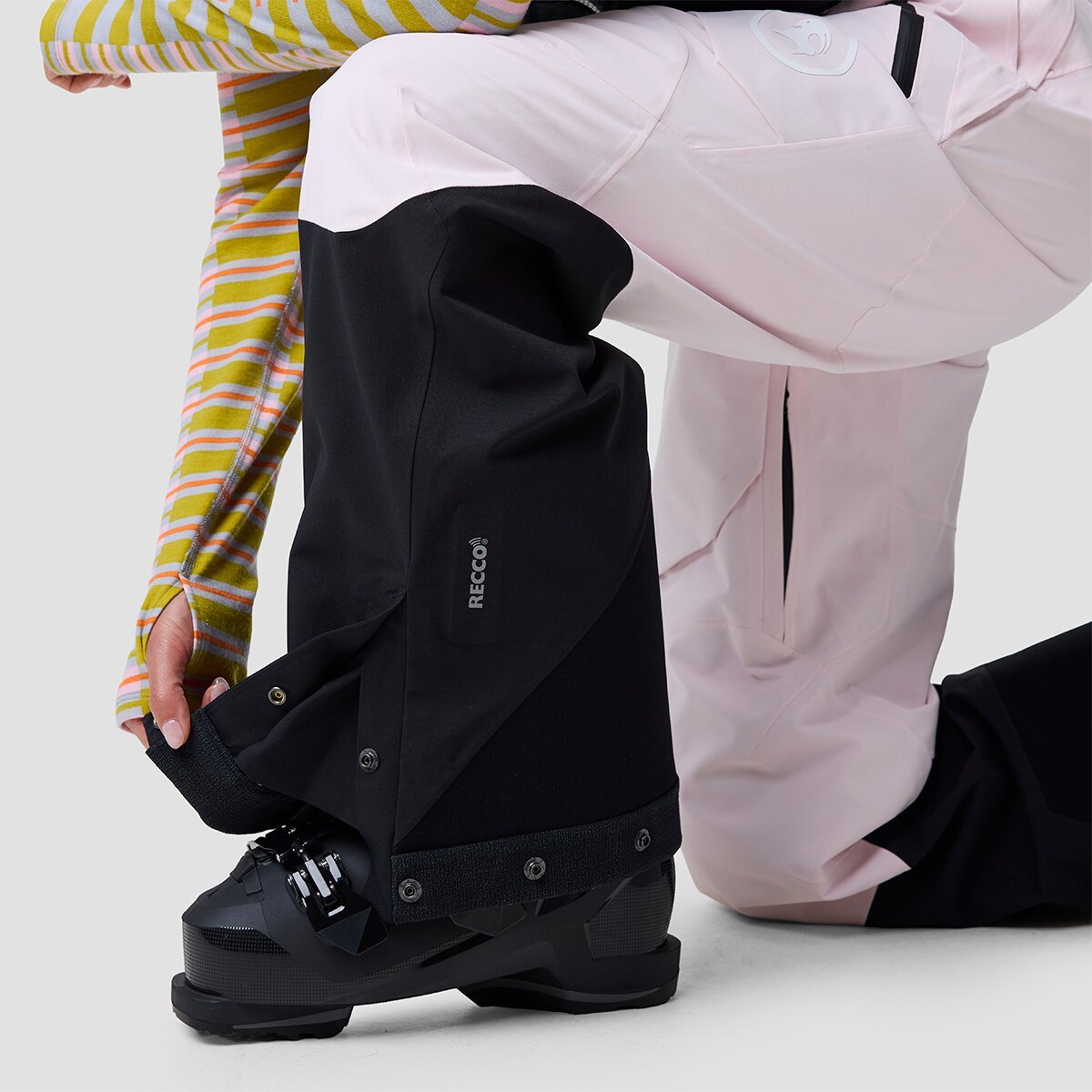 Person wearing Cottonwoods bibs kneeling to adjust snap ankle gusset on kevlar kick panel.