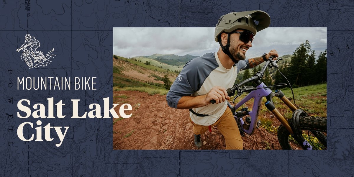 A man smiles as he pushes his mountain bike up a hill. The words, “Mountain Bike Salt Lake City” appear to his left.