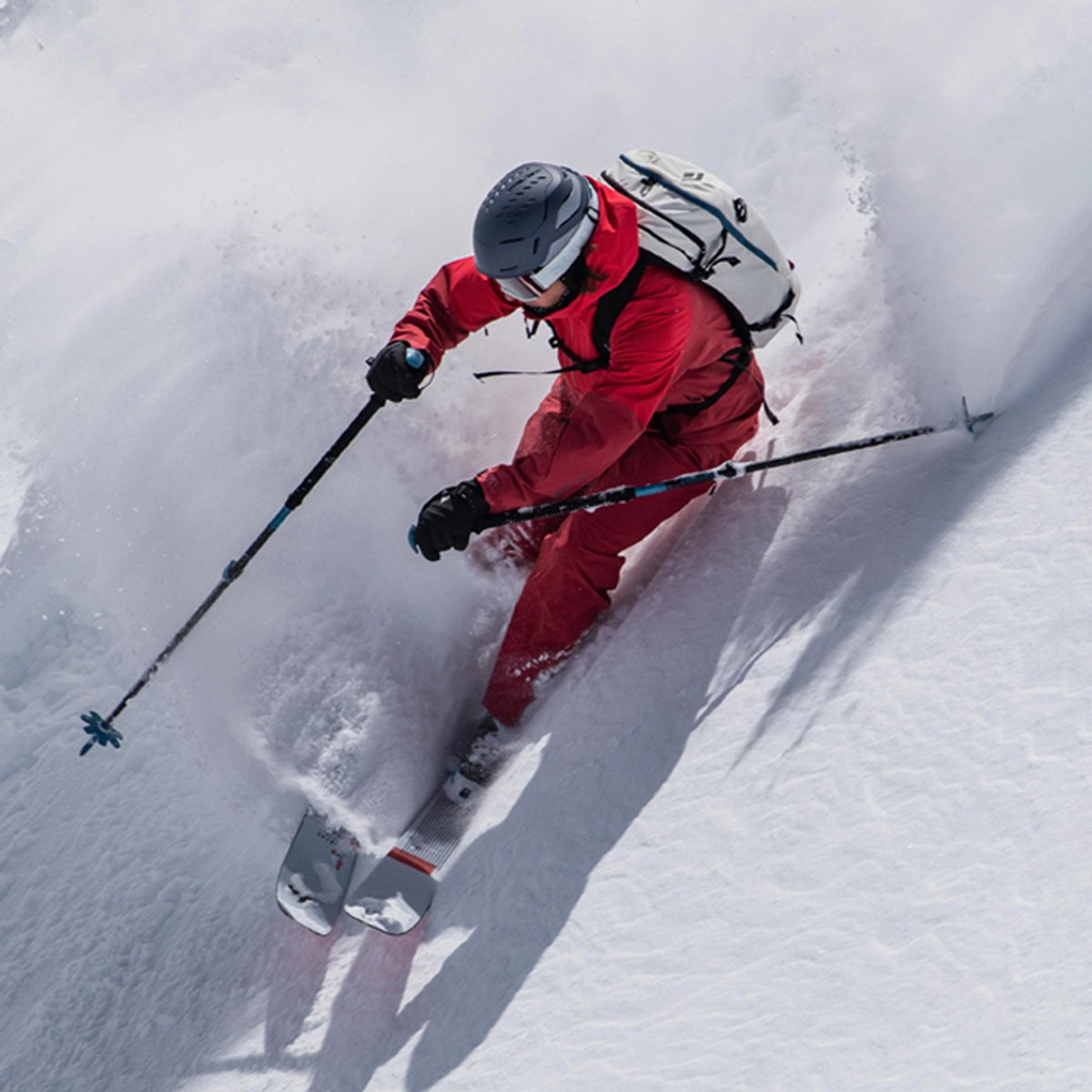 A skier wearing Black Diamond shreds down a slope, snow spraying out behind them.