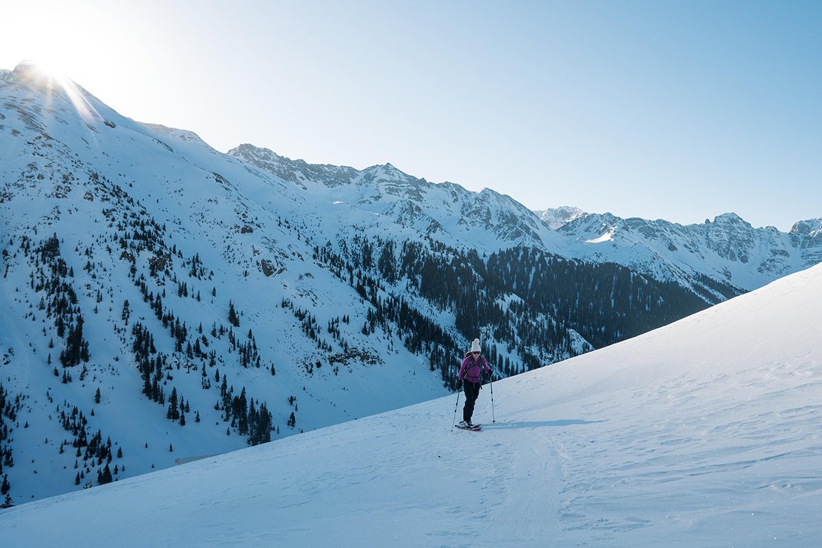 Single skiier standing on snowy face with mountain in the background.