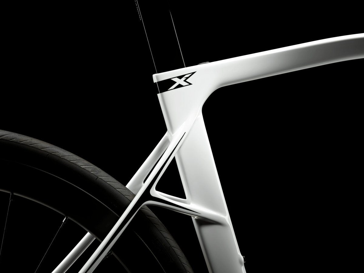 Close-up of white carbon road bike frame showing seat tube and chainstay junction with aero frame geometry in studio lighting