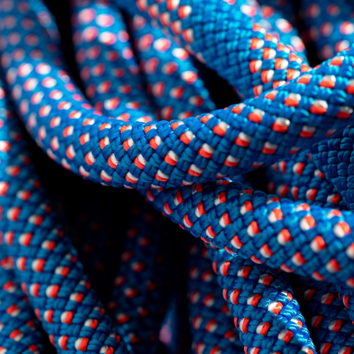 A close-up of a coiled blue climbing rope with red and white flecks.