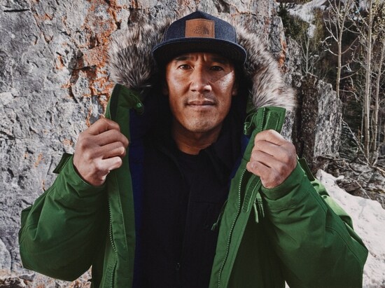 Jimmy Chin adjusts the faux-fur hood of a green parka.