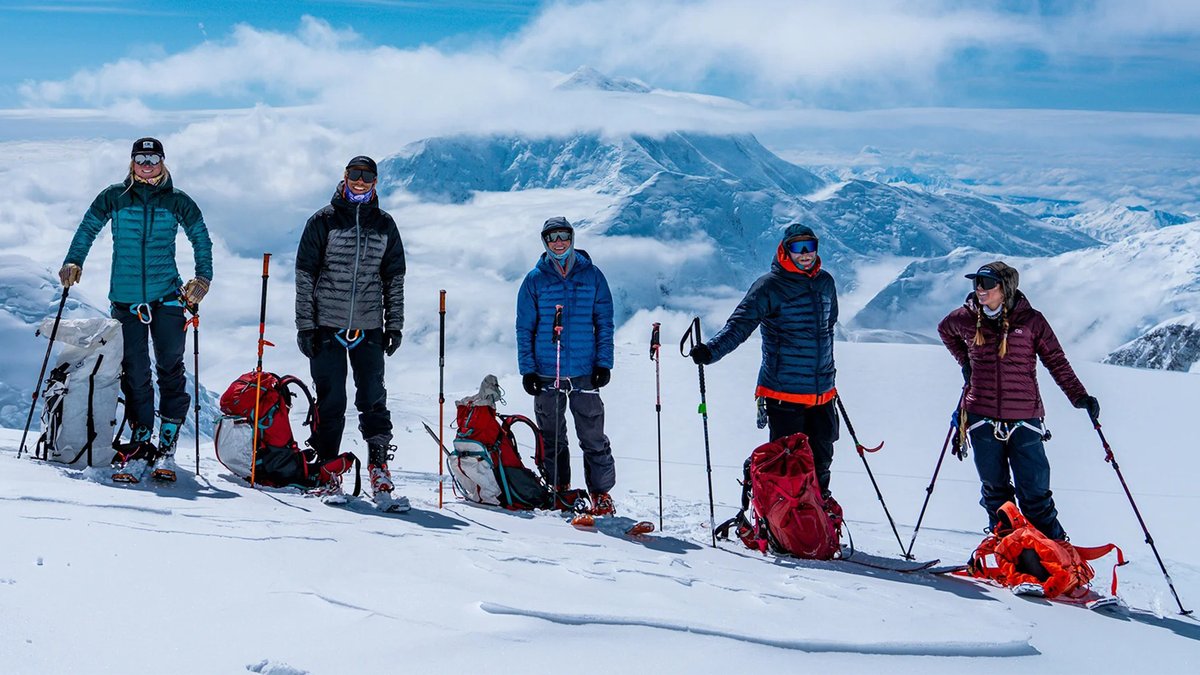 A group of skiers on the slopes wear Outdoor Research Helium jackets.