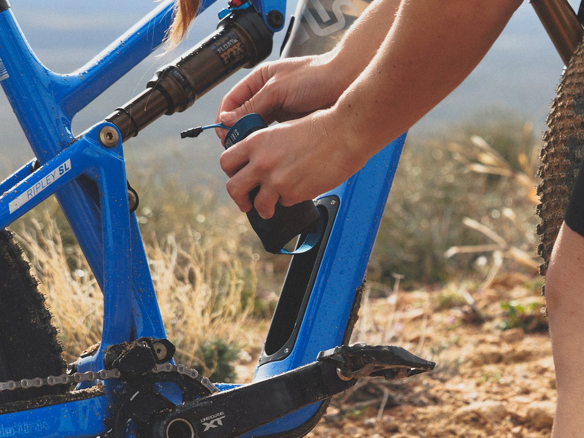 Rider removing integrated storage bag from bike downtube.
