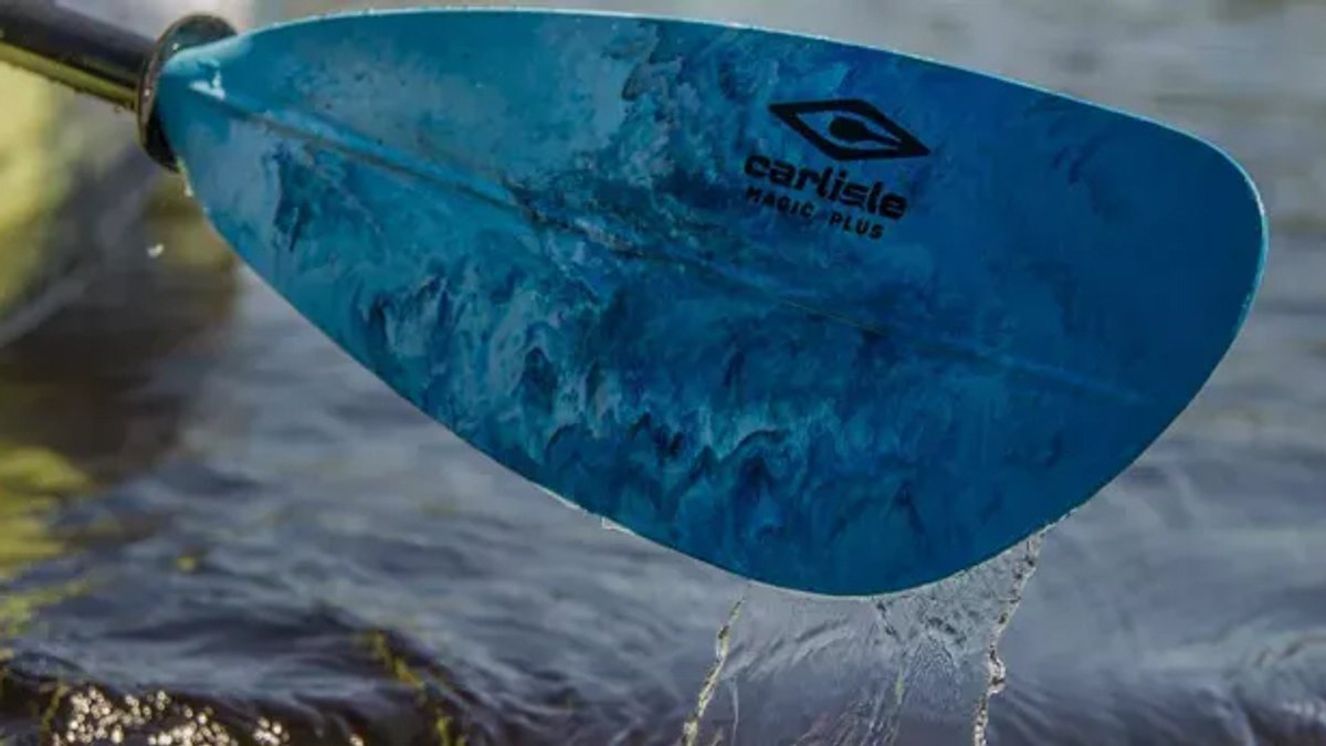 Blue Carlisle paddle with water dripping off the blade during active use on calm water.