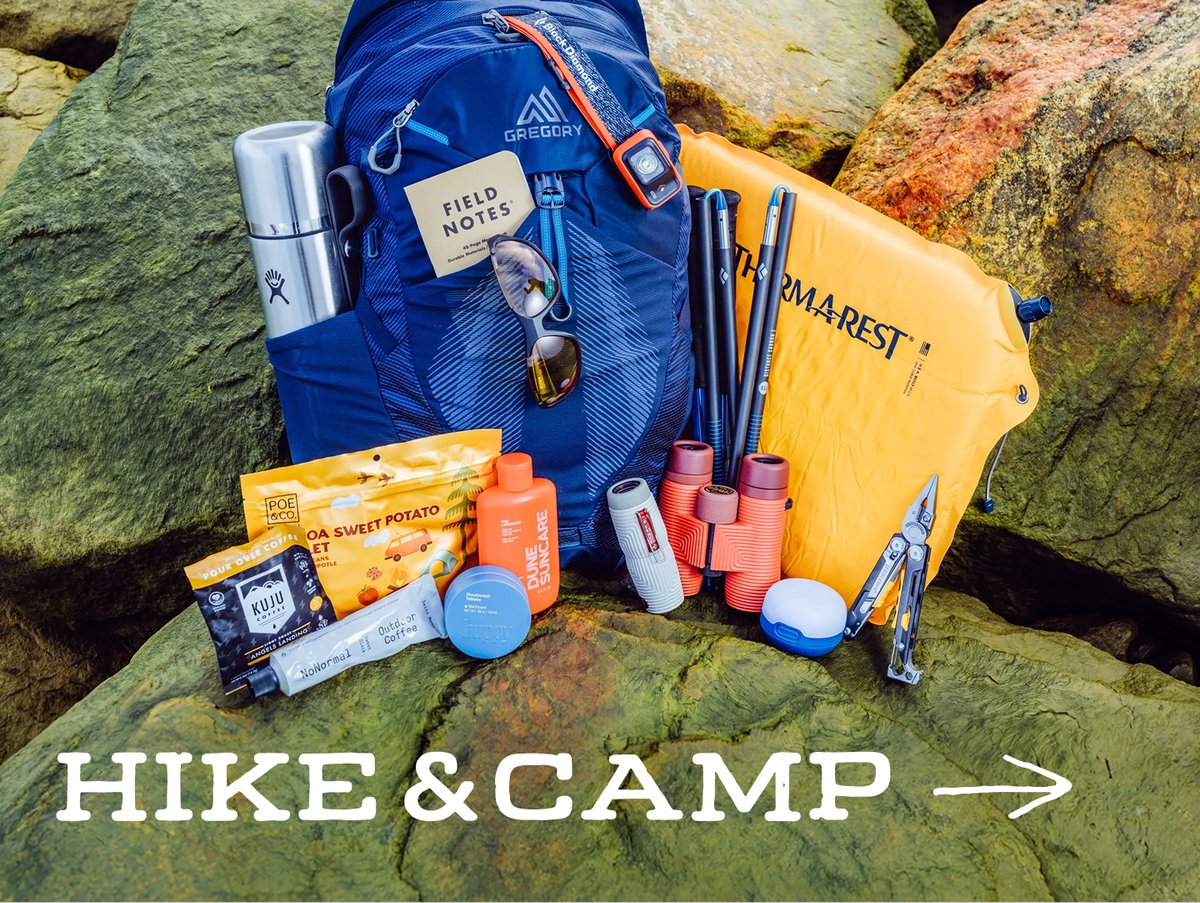 Hiking and camping gear, including a backpack, sleeping pad, trekking poles, binoculars, and a multitool, stacked on mossy rocks: “Hike & Camp.”