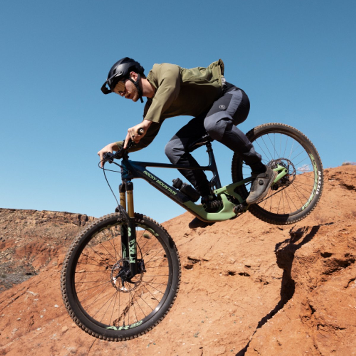 A mountain biker soars through the air while jumping off a sandstone drop. 