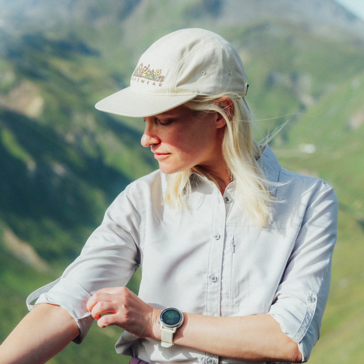 A woman stands outdoors, adjusting the long sleeves on her Canyon top.