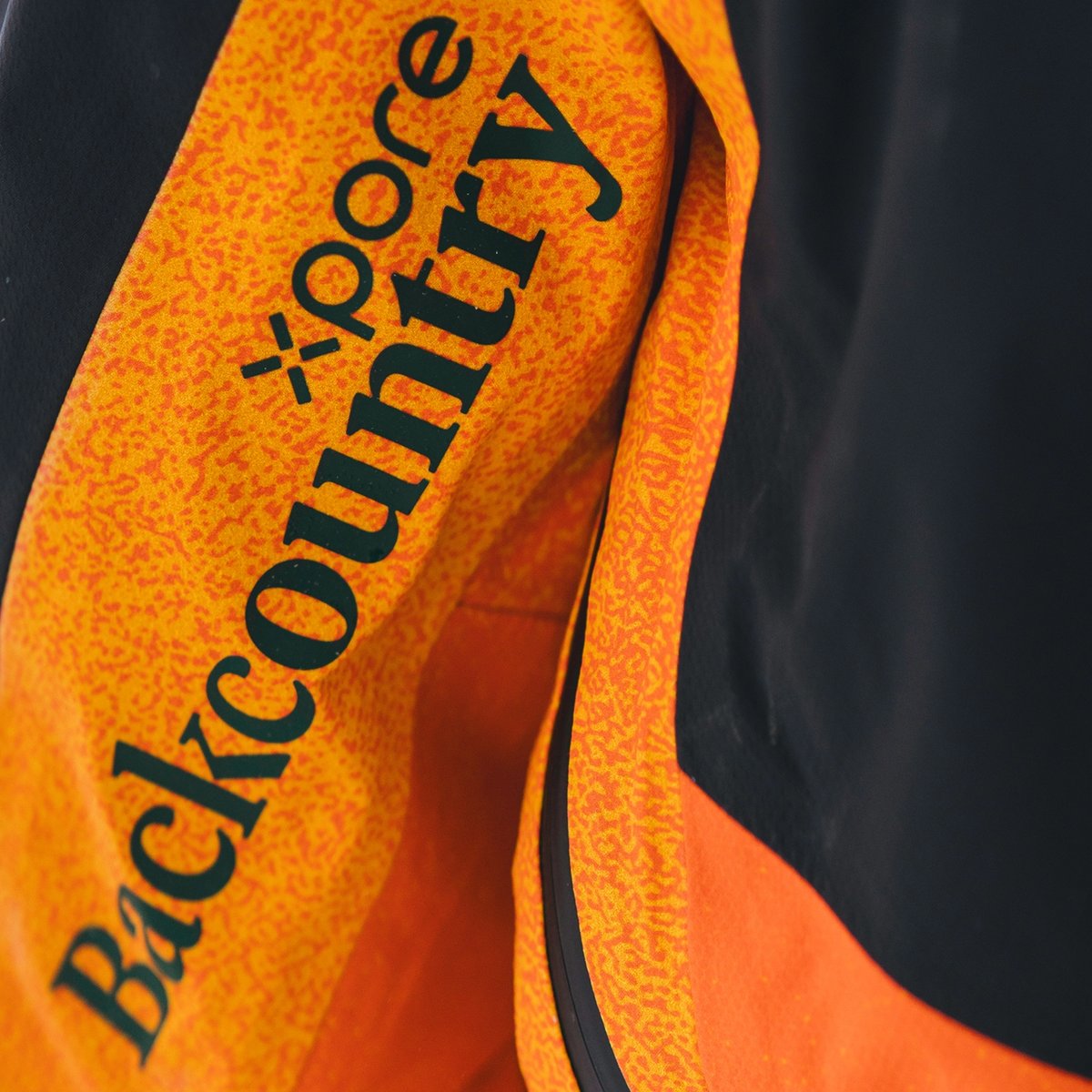 A closeup image of a ski jacket sleeve, showcasing the Xpore and Backcountry logos.
