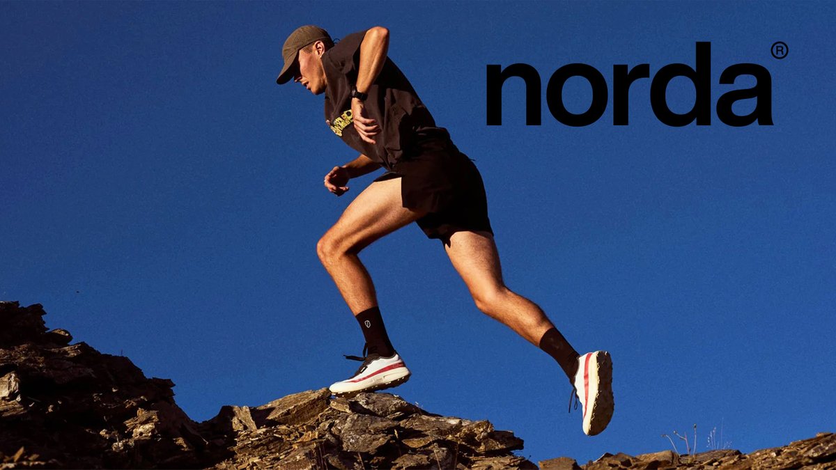 Trail runner in dark athletic gear and Norda shoes leaping over rocky terrain against blue sky with Norda brand logo displayed.