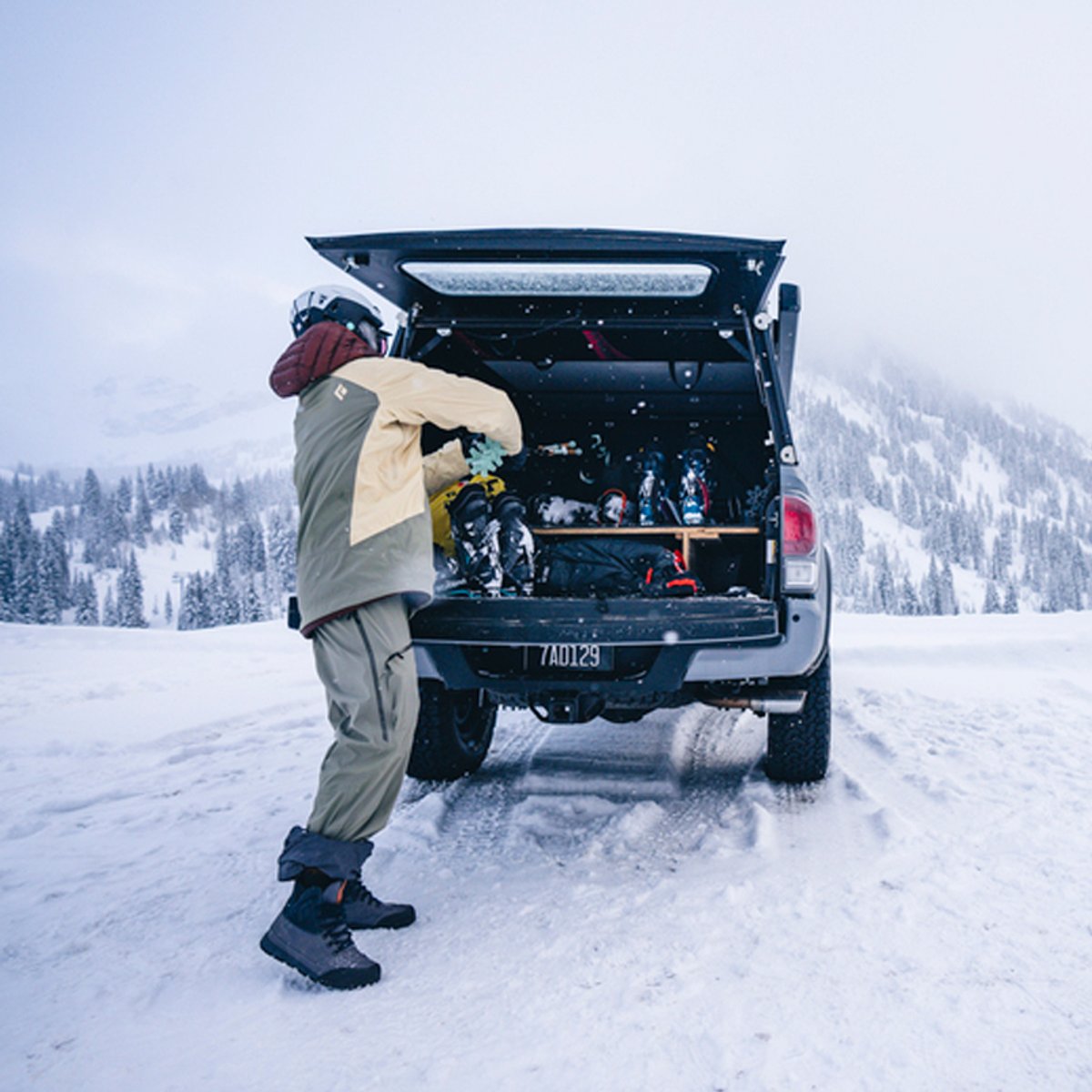 A person wearing Black Diamond pants pulls skis out of the back of a truck.