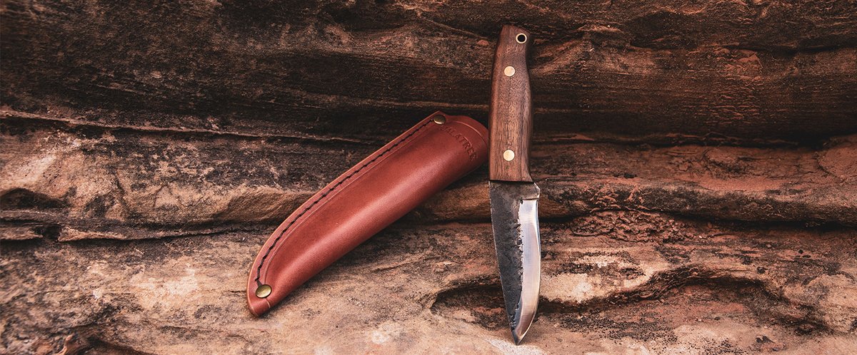 Coalatree Haswell knife and leather sheath leaned up against a rock.