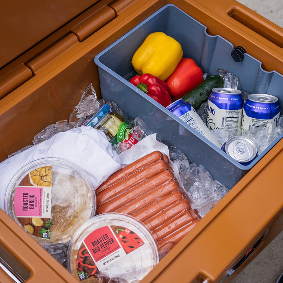 Open RovR RollR cooler packed with ice, drinks, and fresh food, showing the spacious interior and organization bin.