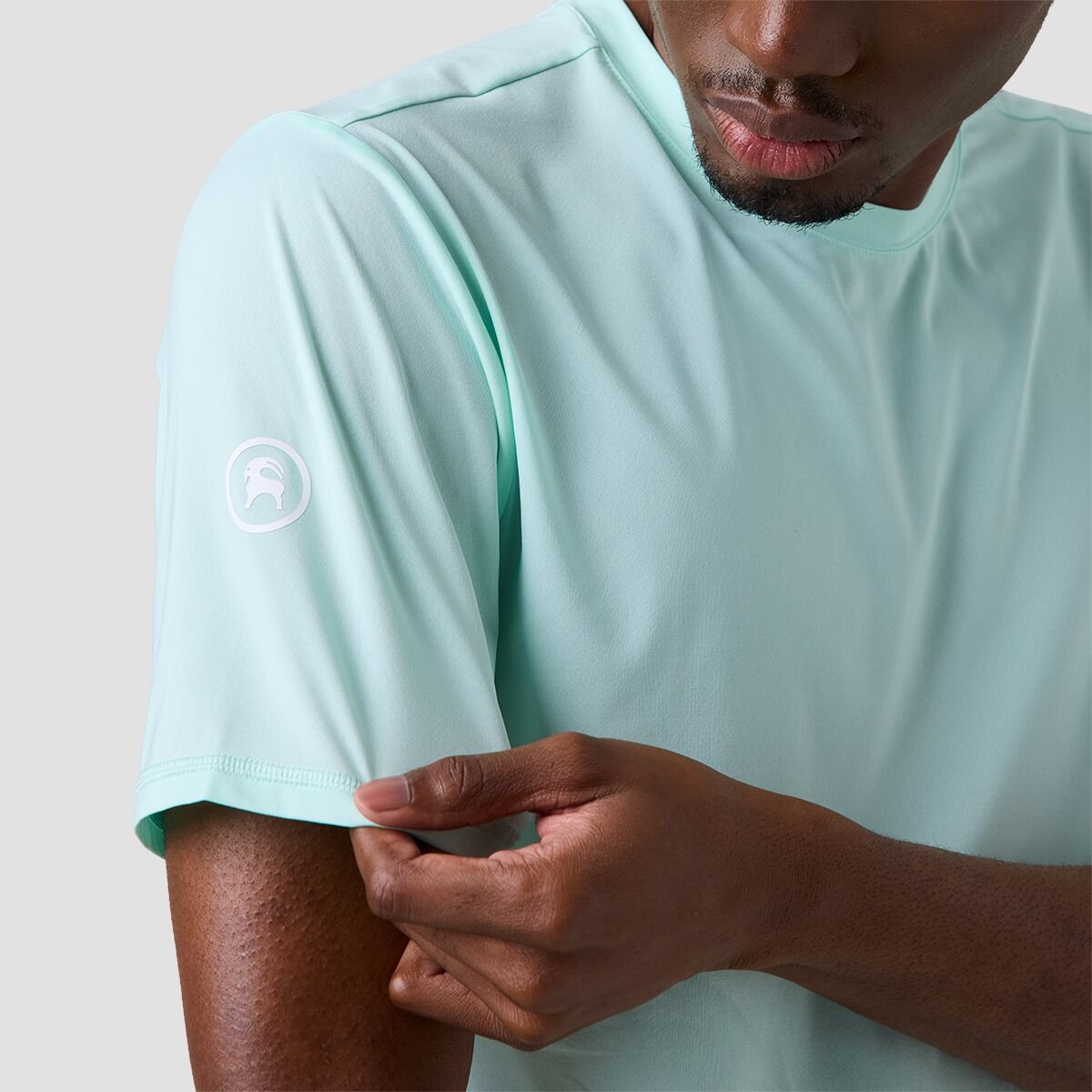 Person wearing Backcountry Tahoe Pro LT sun shirt pulling on sleeve with Backcountry goat logo.