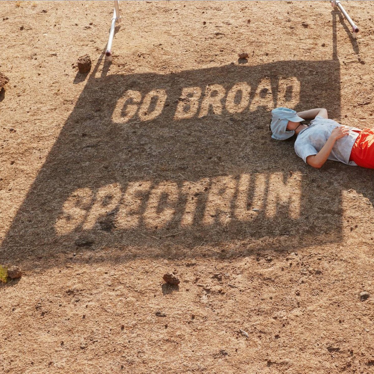 A shadow on the ground reads, "Go Broad Spectrum." A man lounges near the shadow.