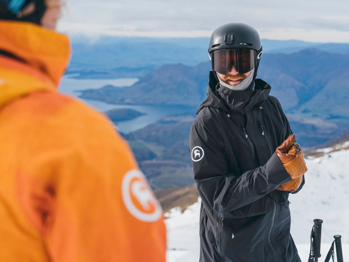 Two skiers talk on top of a mountain
