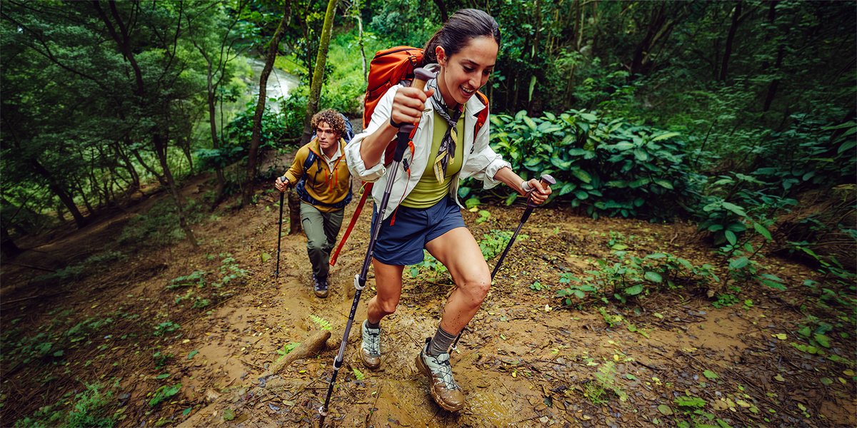 Two people hiking up muddy trail in verdant rainforest wearing Ripstop bottoms.