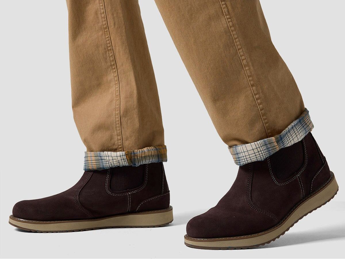 Person wearing cuffed tan pants and dark slip-on boots, shown from mid-calf down.