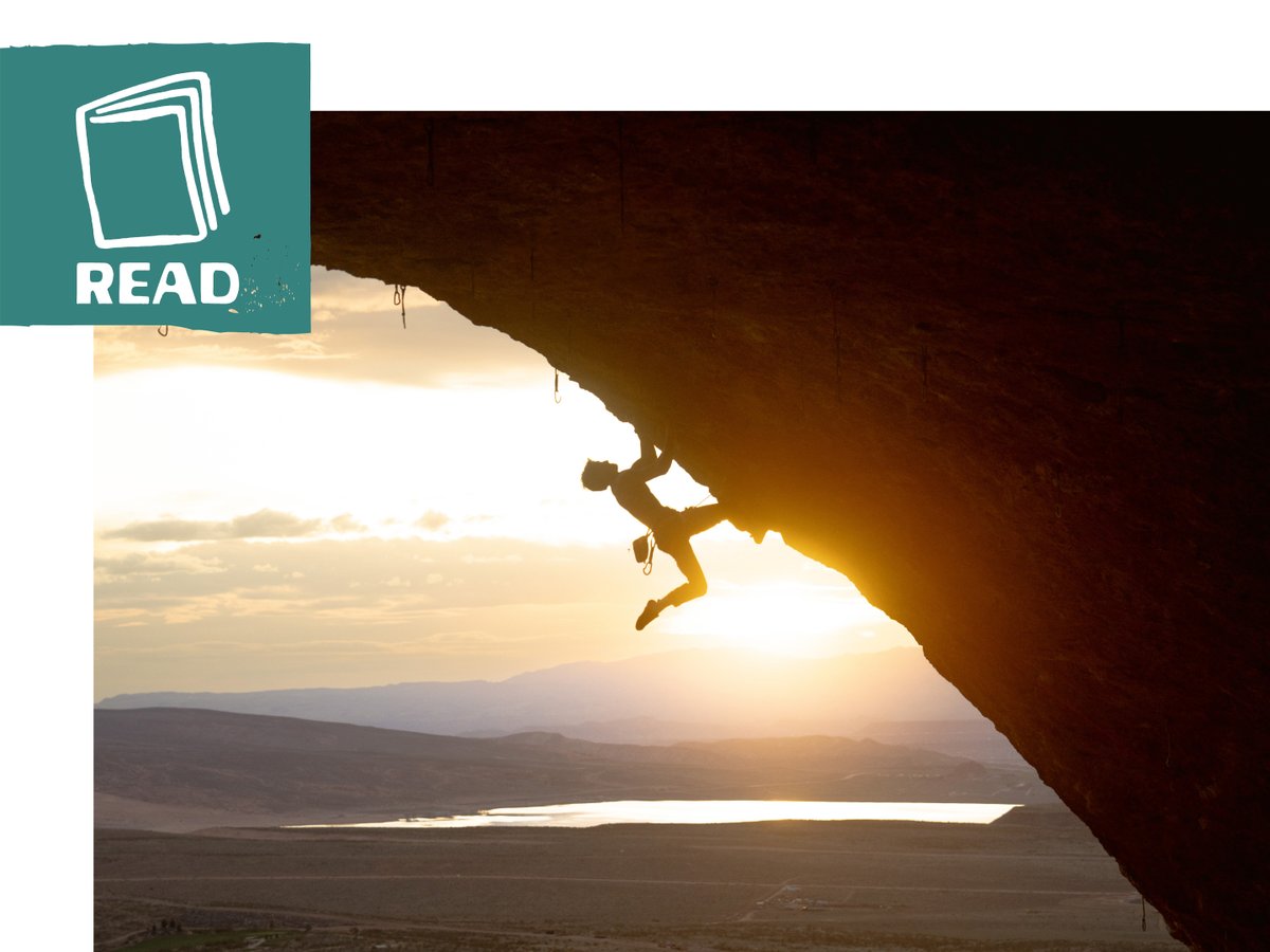 A silhouette of a climber cutting feet on a steep cave climb.